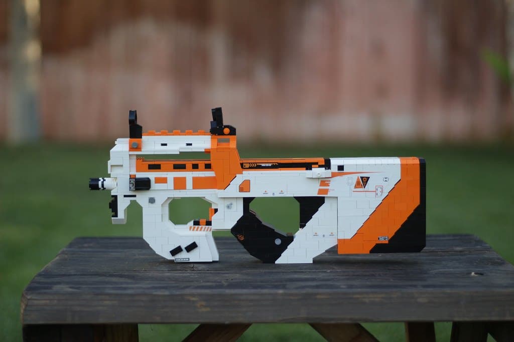 The LEGO P90 Asiimov standing on a wooden table outdoors