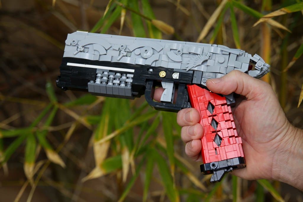 The LEGO Rat King pistol held in front of bamboo